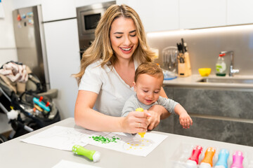 Mother and baby painting together in modern kitchen