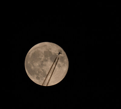 Airplane crossing the full moon at night