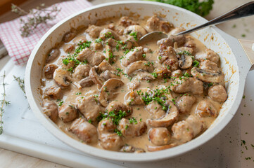 Bratwurst with mushroom cream sauce. Rustic german food in a frying pan