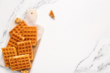Board with tasty Belgian waffles on white background