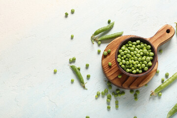 Bowl of green peas and board on light background