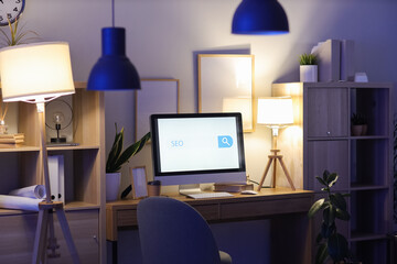 Computer screen with abbreviation SEO and search bar in dark office