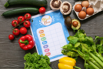 Healthy products and weekly meal plan on wooden background. Diet concept