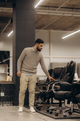 Man Evaluating Office Chairs in a Modern Furniture Store Showroom