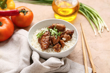 Tasty sweet and sour chicken with rice in bowl, napkin and chopsticks on beige grunge background, closeup