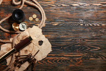 Compass with spyglass, coins, paper and rope on dark wooden background. Pirate concept