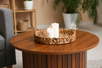 Wicker tray with beautiful candles on table at home, closeup
