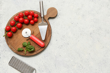 Composition with steel pizza cutter, spatula, grater and fresh tomatoes on light background