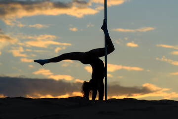 Silhouette of Woman in Handstand Split Pose on Pole at Sunset