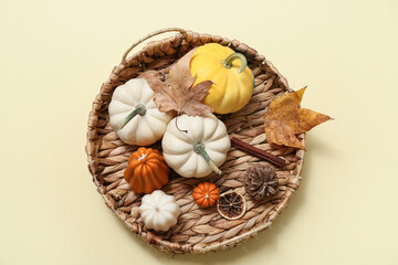 Wicker tray with ripe pumpkins and autumn candles on color background