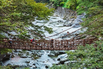 Travelers on a vine bridge in Iya Valley. © Wirestock