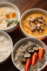 4 types of porridge in white bowls on a wooden background, oatmeal, corn, millet and rice