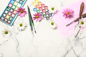 Painting with artist brushes, paints and flowers on white marble background