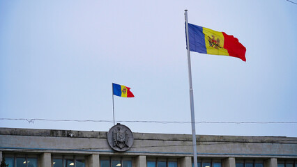 Moldovan flags flutter against a gray sky above a government building in Chisinau during the early...