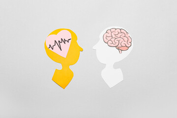 Paper human heads with heart and brain on grey background. Emotional and rational thinking concept