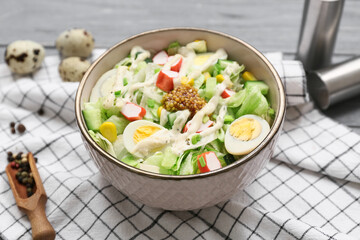 Bowl of salad with crab sticks, corn and cucumber on grey wooden background