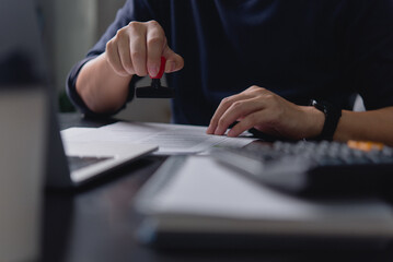 A business professional stamping an official document in an office environment, symbolizing document approval and business paperwork processes.