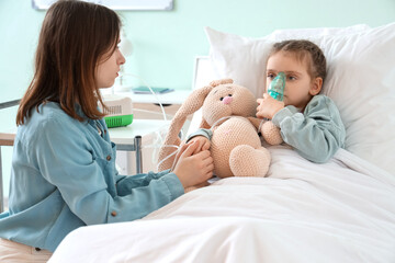 Woman and her ill little daughter with nebulizer in clinic