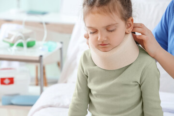Nurse putting cervical collar on little girl's neck in clinic