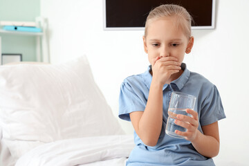 Little girl with nausea and glass of water in clinic