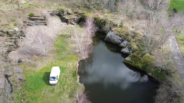 Vanlife avec van blanc au bord d'un &eacute;tang dans la montagne noire, vue a&eacute;rienne d'un drone avec un van en mouvement.