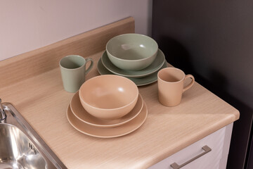 Holder with clean dishes near sink on counter in kitchen
