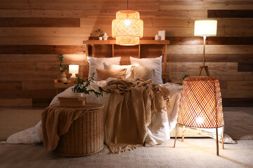 Interior of stylish bedroom with cozy bed and glowing lamps at night