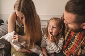 Happy family meets new baby. Mom, dad, older daughter and newborn son. Parents introduce older sister to baby	
