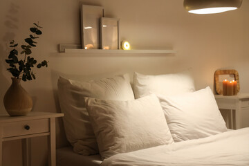 Cozy bed and glowing lamps in modern bedroom at night