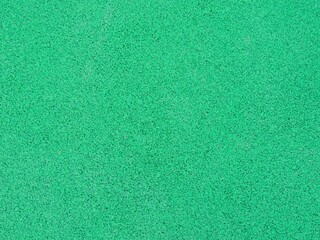 green single color textured grainy background material close-up full frame, rubber crumb coating for sports and fitness and for paving playgrounds, soft springy elastic artificial material