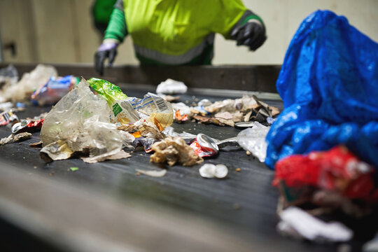 Worker sorting plastic waste on a recycling conveyor belt
