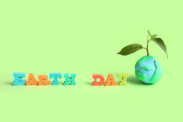 Obraz premium Planet Earth with plant and words EARTH DAY on green background. World Earth Day celebration