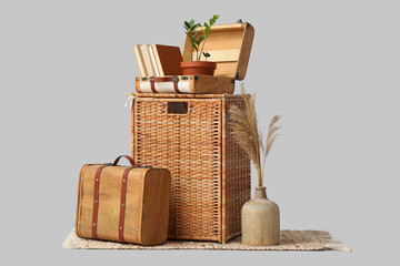 Wicker basket with suitcases and pampas grass on grey background