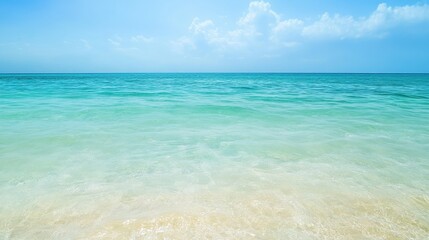Obraz premium Tropical Ocean Paradise: Tranquil Turquoise Waters Meet Pristine Sandy Beach Under a Bright Blue Sky with Soft Clouds