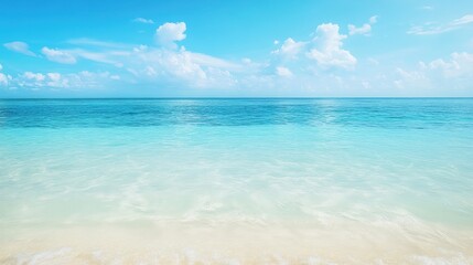 Obraz premium Tranquil Beach Scene: Turquoise Ocean Waves Gently Lapping onto a White Sand Beach Under a Blue Sky with Fluffy Clouds