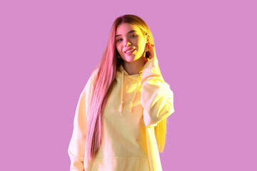 Stylish young woman in yellow hoodie on color background