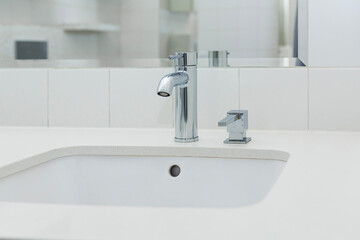 Modern bathroom sink with sleek faucet and soap dispenser in bright, minimalistic setting