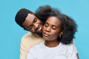 Fototapeta premium Happy young couple with natural hair against a blue background, showcasing love and connection in a vibrant and modern style