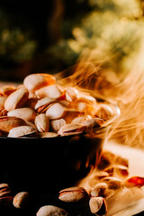 Warm toasted pistachios in a bowl with smoke rising, showcasing a cozy snack moment outdoors