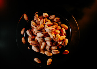 Pistachio nuts piled in a black bowl creating an elegant display in a dimly lit setting