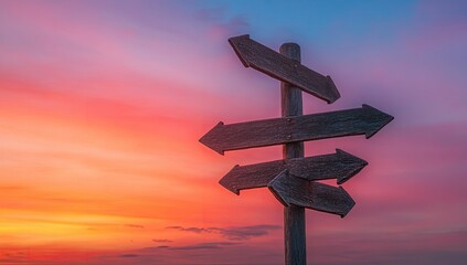 Wooden signpost with multiple directions at sunset.  A weathered wooden signpost displays multiple blank arrows, indicating different paths.