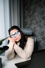 Exhausted and tired office worker female with painted eyes on stickers sleeping at workplace. Woman...