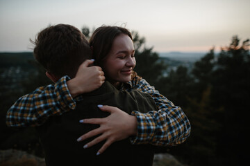 Fototapeta premium Beautiful young woman in the arms of her boyfriend at sunset in the mountains.