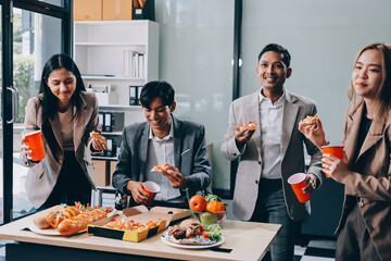 Asian office colleagues and friends enjoy a daytime BBQ with pizza and beer, celebrating Halloween and cheering for their favorite soccer team, creating a lively atmosphere filled with joy.