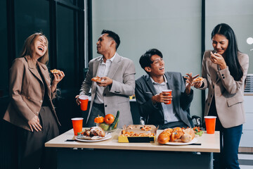 Asian office colleagues and friends enjoy a daytime BBQ with pizza and beer, celebrating Halloween and cheering for their favorite soccer team, creating a lively atmosphere filled with joy.
