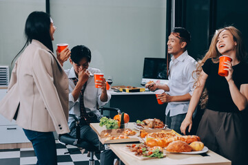 Asian office colleagues and friends enjoy a daytime BBQ with pizza and beer, celebrating Halloween and cheering for their favorite soccer team, creating a lively atmosphere filled with joy.