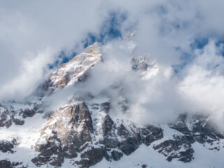 The Matterhorn's rugged, snow covered peaks rise dramatically, partially obscured by clouds, with...