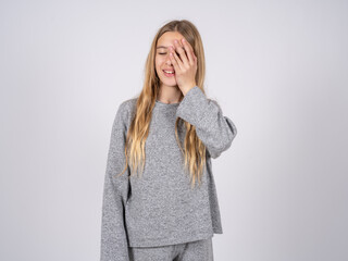 beautiful caucasian girl wearing grey track-suit  makes face palm and smiles broadly, giggles...