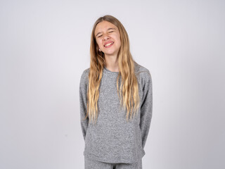 Obraz premium Positive beautiful caucasian girl wearing grey track-suit with overjoyed expression closes eyes and laughs shows white perfect teeth