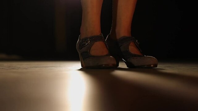 Low POV of lit stage floor, flamenco dancer tapping her foot. Static